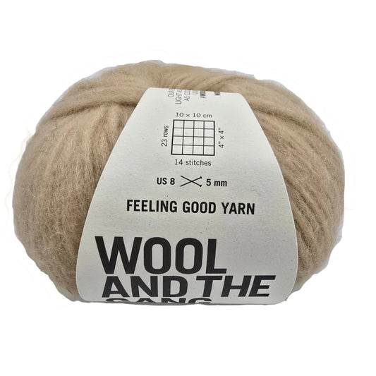 Image of a single ball of Feeling Good Yarn by Wool And The Gang in the color Blonde Beige with label on a white background.