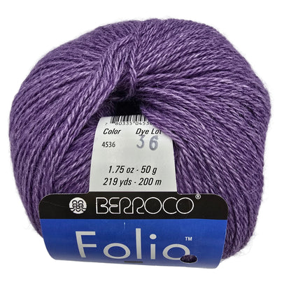 A ball of purple variegated yarn with a white and blue Berroco Folio tag attached, photographed on a plain light background.