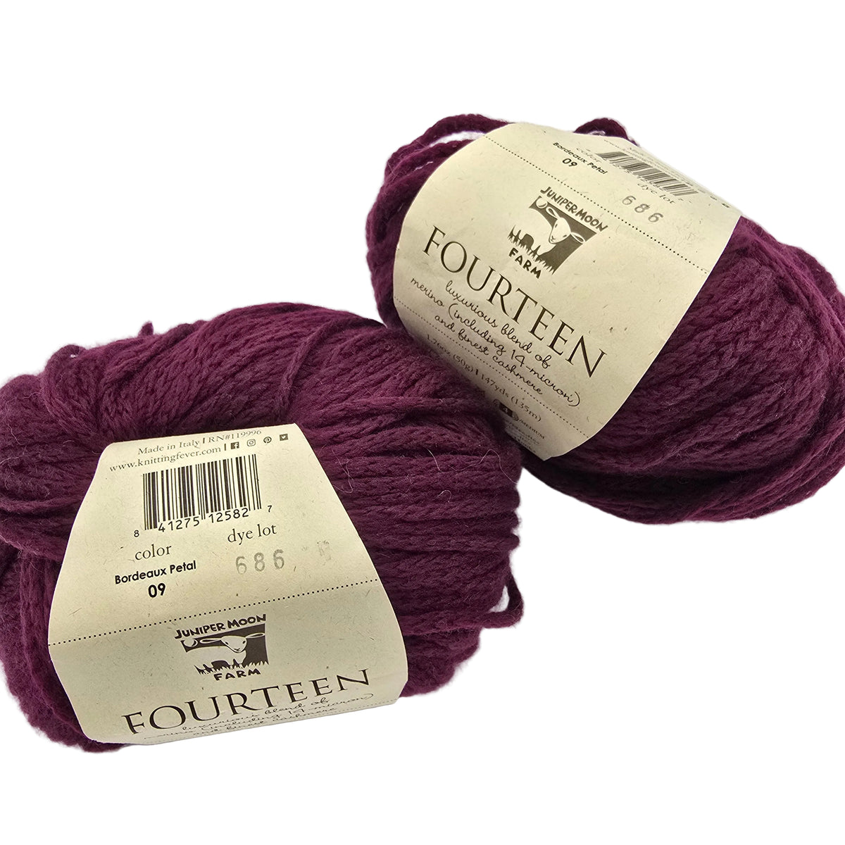 Image of Two Balls of Fourteen Yarn by Juniper Moon Farm in the color Bordeaux Pearl a rich burgundy with labels on a white background.