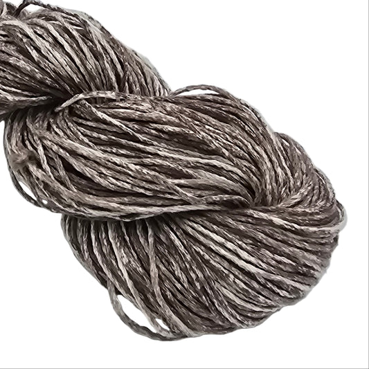 Close-up image of Good Earth Adorn yarn by Fibra Natura in the color Alder which is brown and white on a white background.