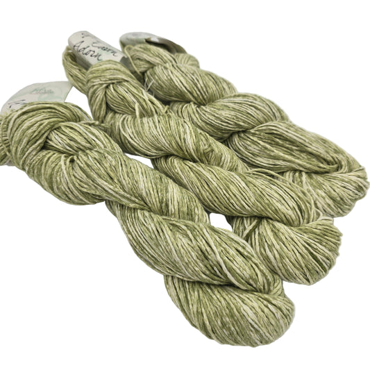 Three skeins of Good Earth Adorn yarn by Fibra Natura in color Lettuce which is a green and white with labels on a white background.
