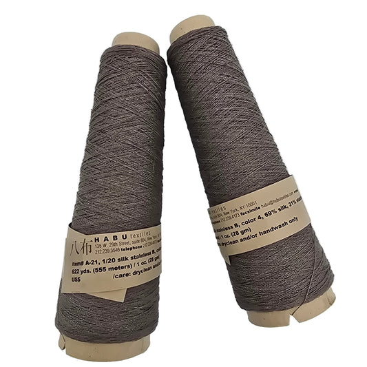 Two cones of Habu Textiles A-21, 1/20 Silk and Stainless yarn with labels on a white background