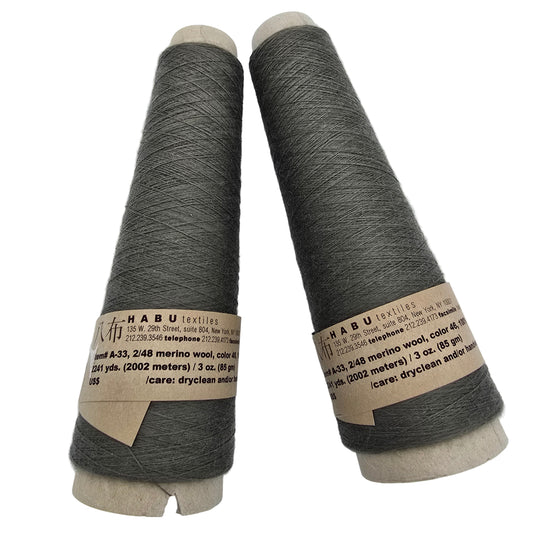Two skeins of gray Habu Textiles yarn with labels on a white background