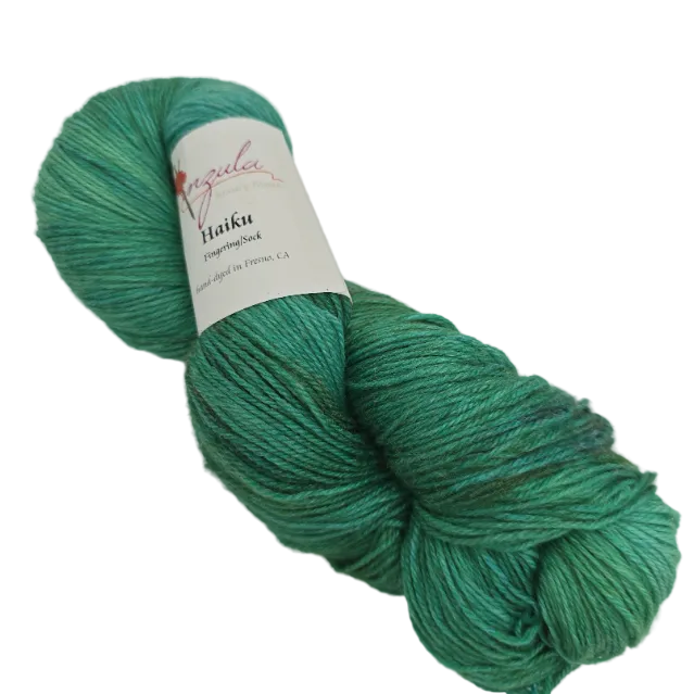 Image of a single skein of Haiku by Anzula in the color Peacock with label on a white background.