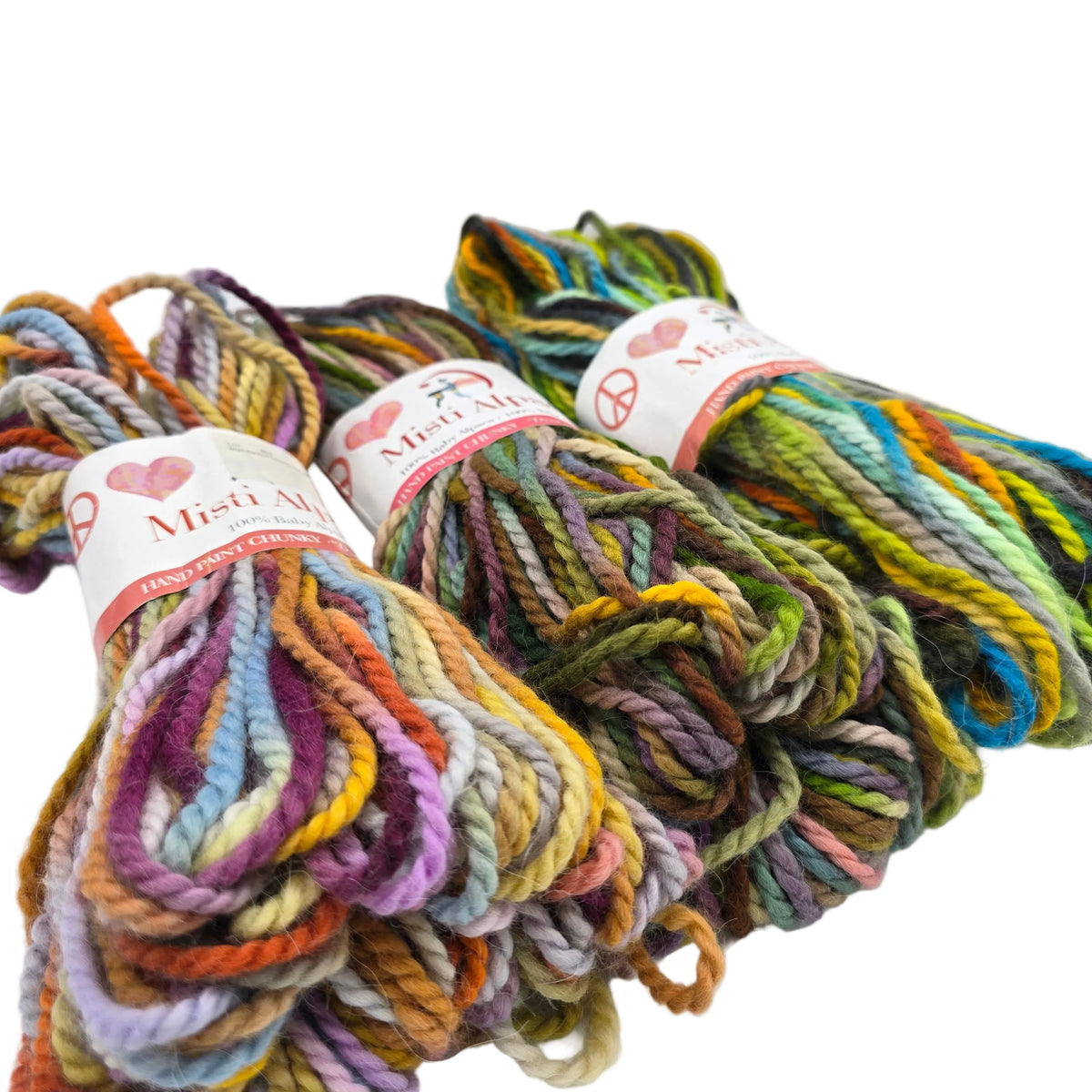 Three skeins of Hand Print Chunky Yarn by Misti Alpaca a hand-dyed cotton yarn in a variegated multicolor pattern, displayed on a clean white background.