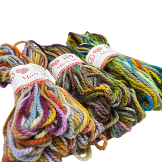Three skeins of Hand Print Chunky Yarn by Misti Alpaca a hand-dyed cotton yarn in a variegated multicolor pattern, displayed on a clean white background.