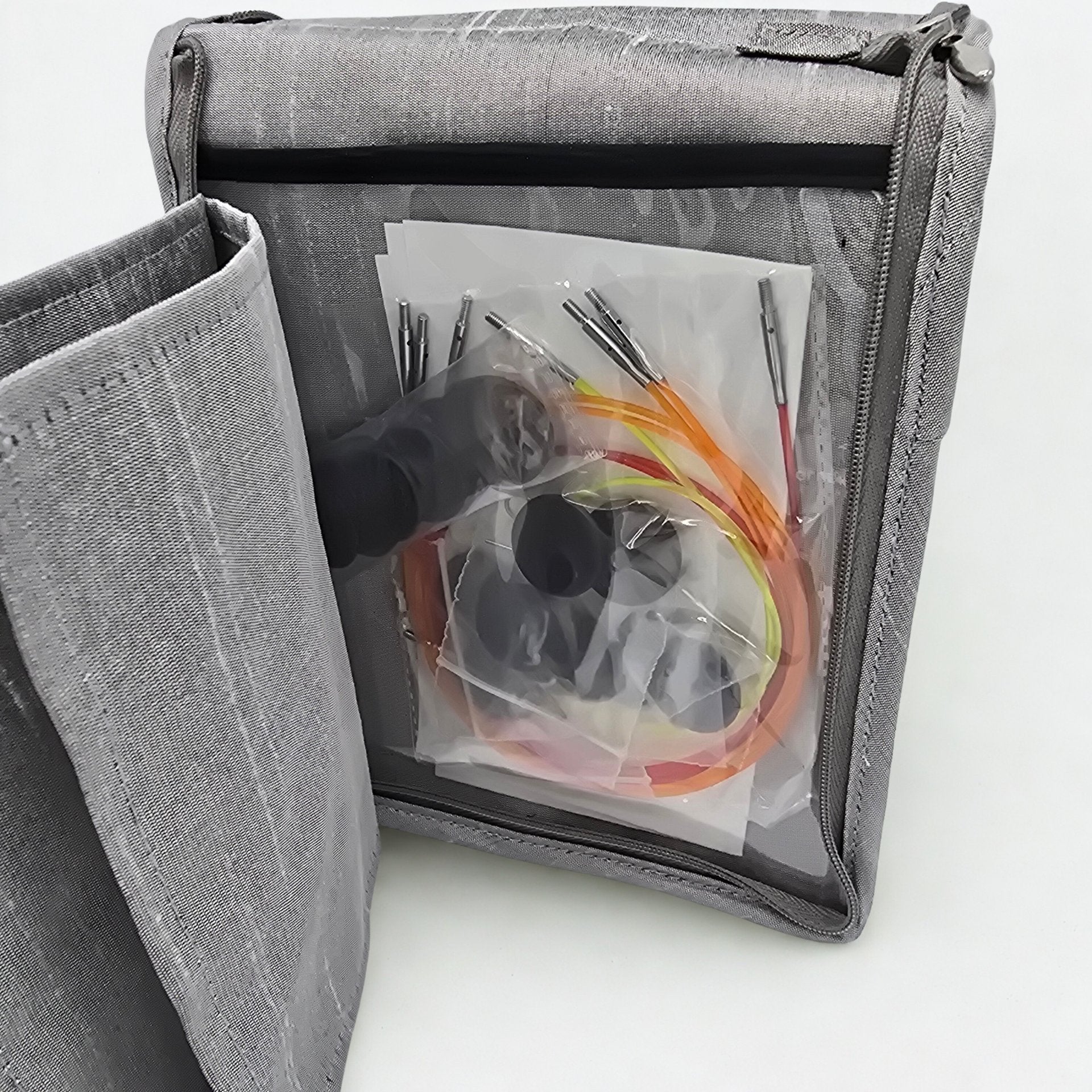 Gray fabric bag with clear window showing knitting needle kit contents on a light gray background
