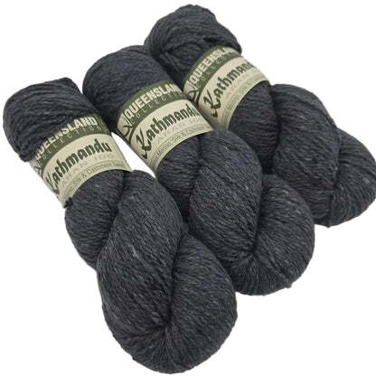 Three Skeins of Kathmandu Aran 100 yarn by Queensland Collection in color  2 Slate Gray with labels on a white background.