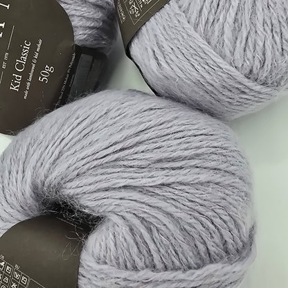 Two skeins of gray yarn with labels on a light background