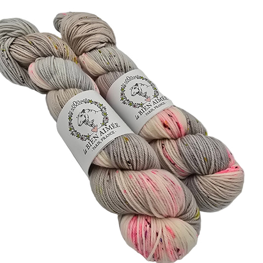 Image of two skeins of wool from the brand La Bien Aimee in the color Fiori (which is a mix of pink, grey and cream) with labels on a white background.