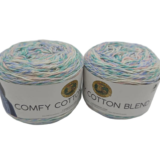 Image of Two Cakes of Lion Brand Comfy Cotton Blend yarn in the color Sugarcane  with labels on a white background.