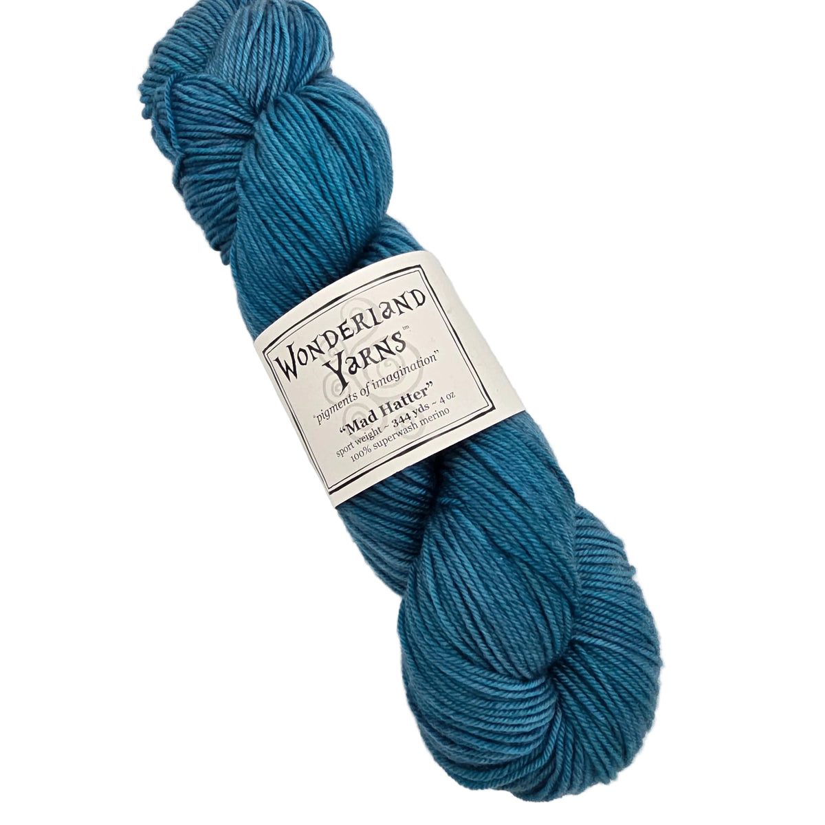 A skein of teal blue yarn with a white paper label reading 'Wonderland Yarns' and 'Mad Hatter', photographed on a plain light background.