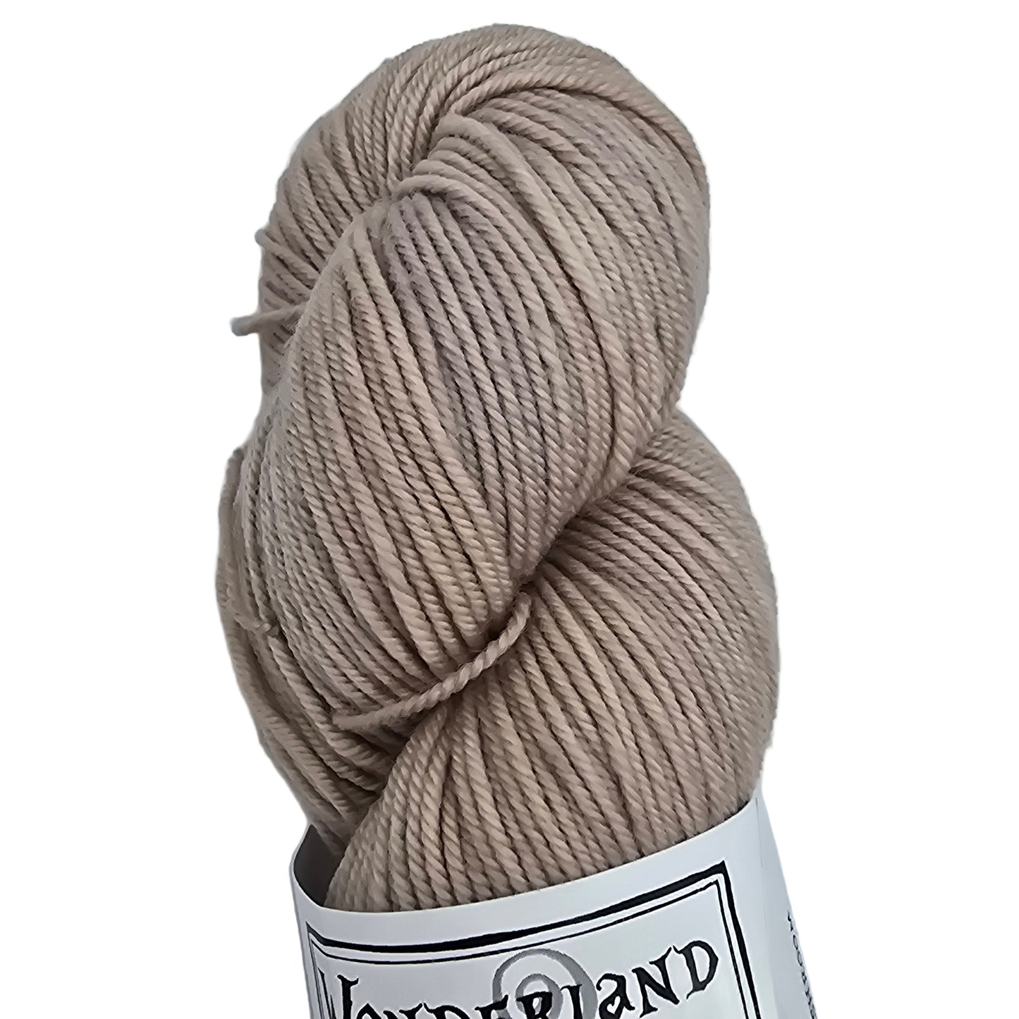Close up image of a single skein of Mad Hatter by Wonderland Merino Sport yarn in Mushroom which is a light beige  color with label on a white background.