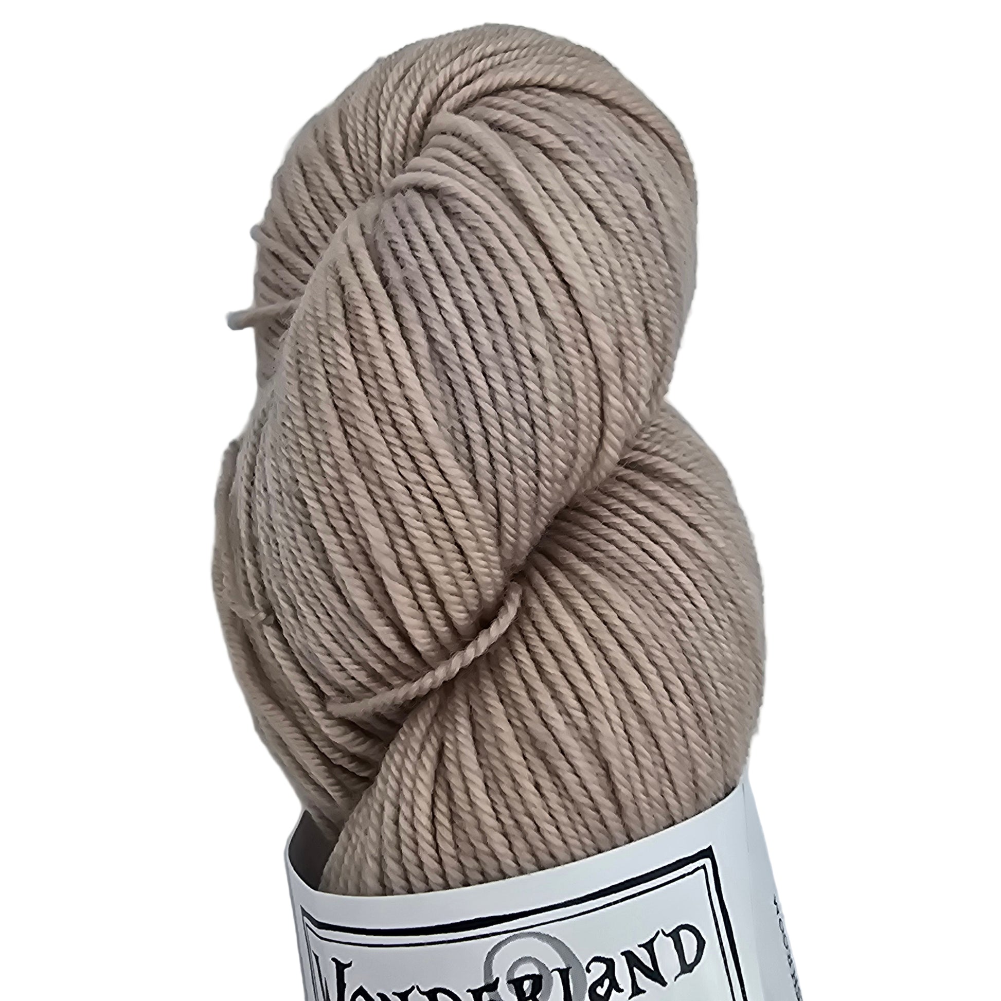 Close up image of a single skein of Mad Hatter by Wonderland Merino Sport yarn in Mushroom which is a light beige  color with label on a white background.