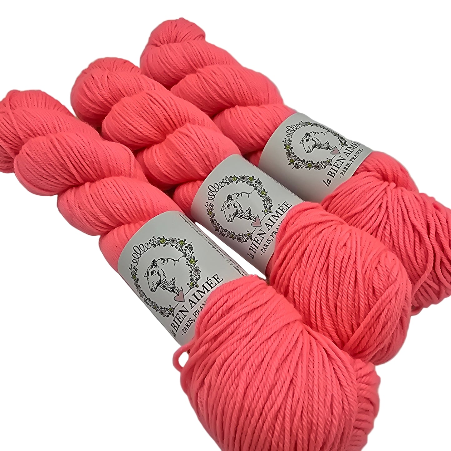 Image of multiple skeins of Merino DK by La Bien Aimee yarn in color Fluoro Morganite (Salmon pink) with labels on  a white background.