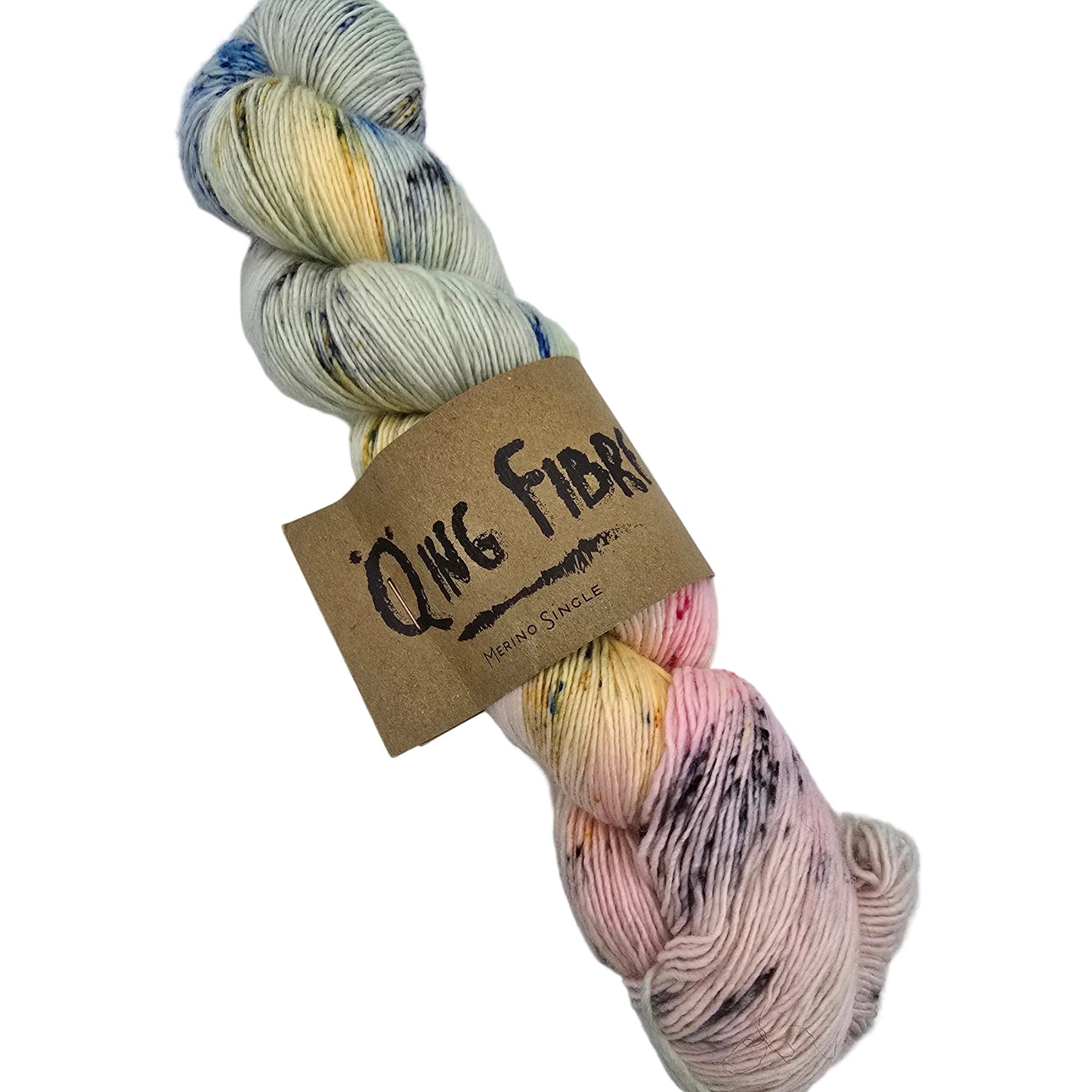 A skein of hand-dyed Merino Single  fingering yarn from Qing Fibre, wrapped with a brown kraft paper label. Cthe color name is Soft Grey and features variegated colors of cream, pale yellow, dusty pink, and light blue with dark purple and black speckles, set against a plain white background.