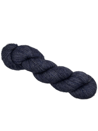 Image of a single skein of Monologue yarn by Leading Men Fiber Arts in the color Dames at Sea which is Navy Blue with no label on a ehite background.