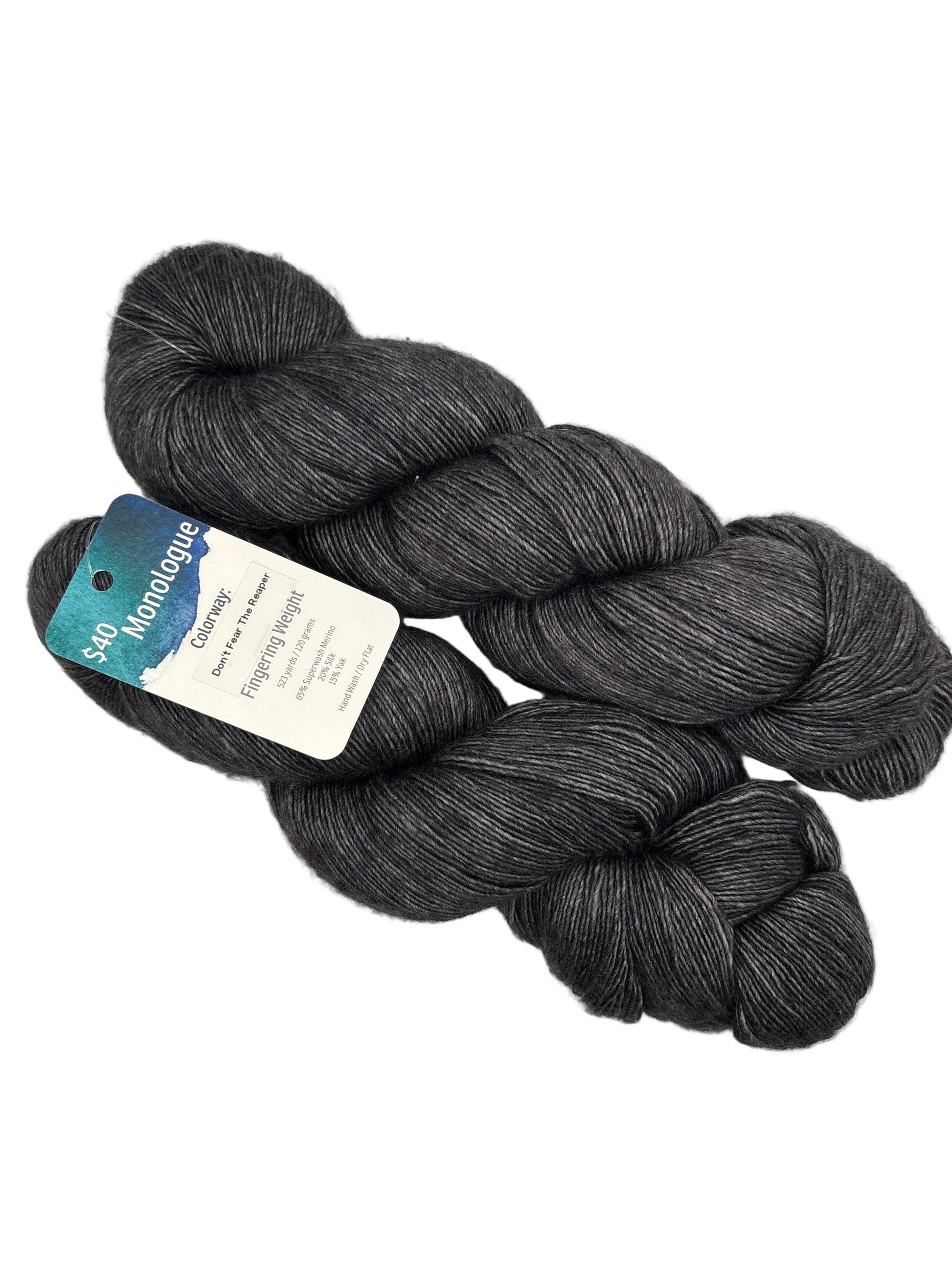 Two skeins of Monologue by Leading Men Fiber Arts - Don’t Fear the Reaper yarn with label attached on white background.