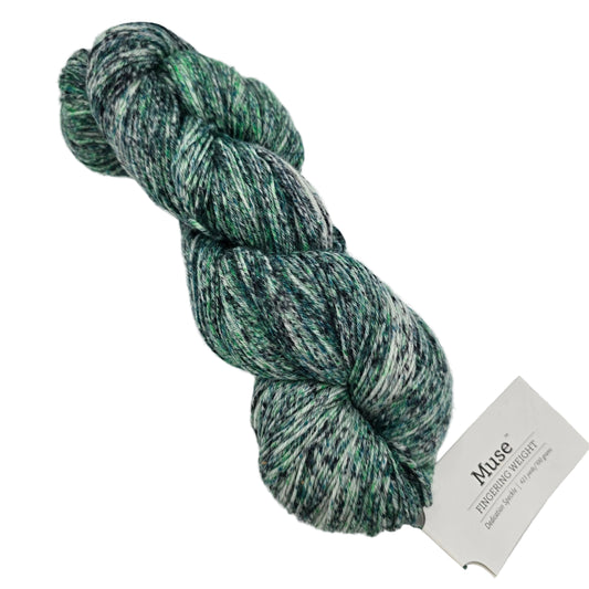 Image of a single skein of Muse Hand Painted Sock Yarn by Knit Picks  in the color Dedication Speckle 28799 with label on a white background.