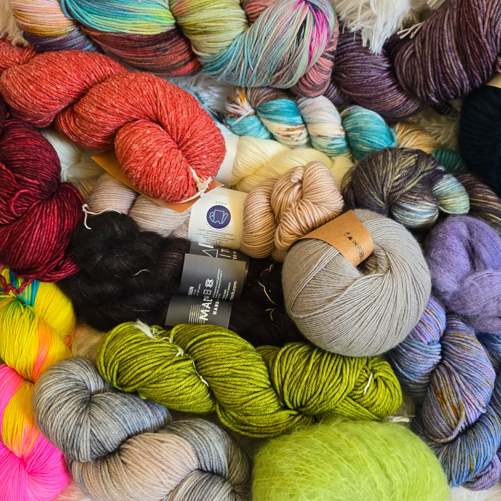 Image of multiple skeins and balls of yarn im multiple colors with some labels showing and no visible background.