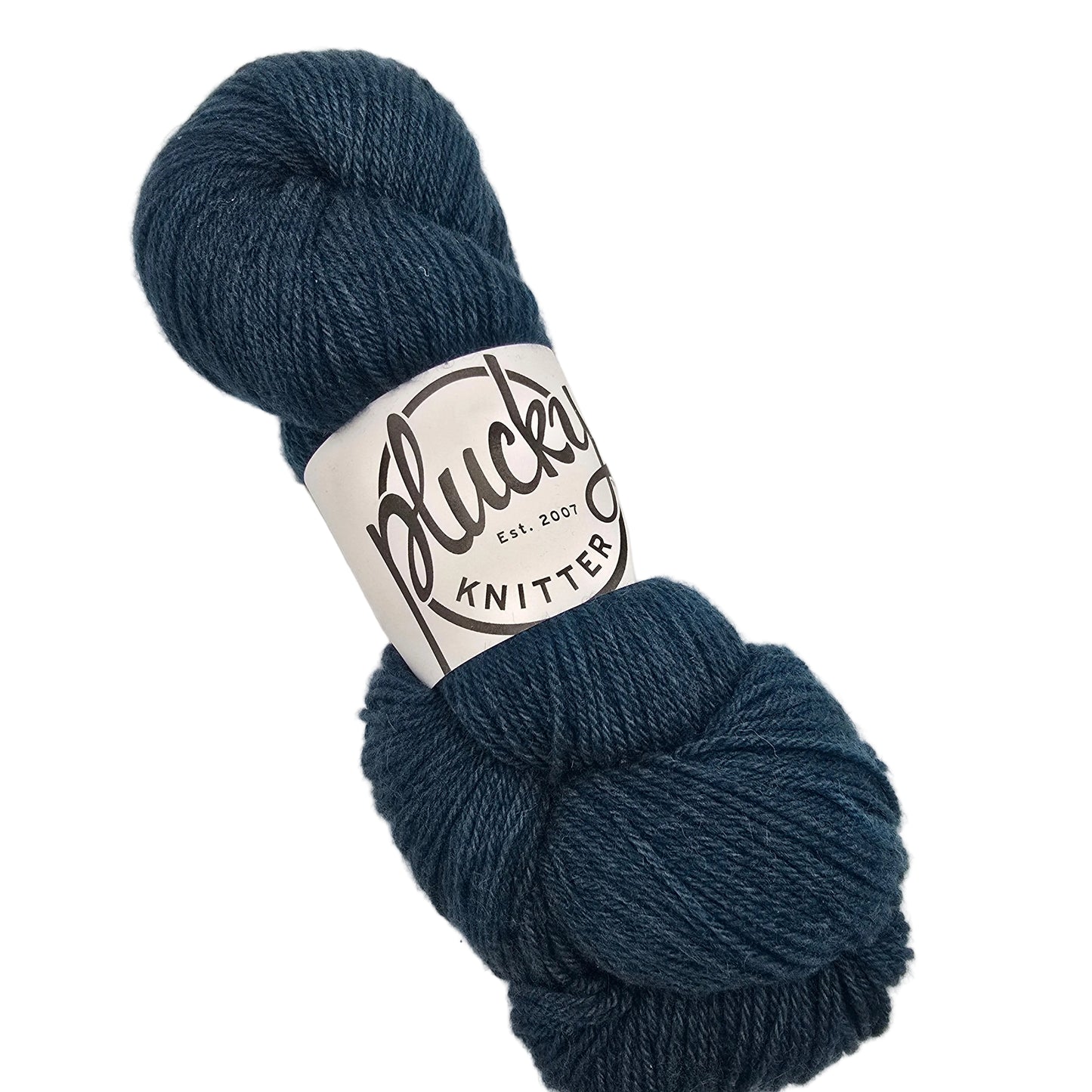 A skein of Oxford_yarn by_Plucky_Knitter_in the color_Jacque a blue yarn with a white paper label on a white background.