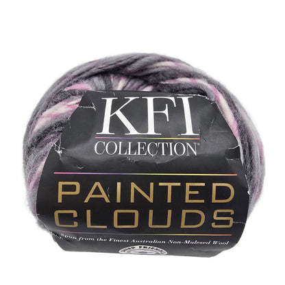 A ball of KFI Collection 'Painted Clouds' yarn with a black paper label, showing variegated colors of gray, purple, and pink in the wool on a white background.
