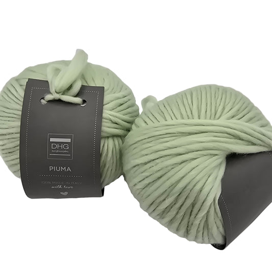 Image of two balls of Piuma by DHG Ultra Soft bulky Italian Merino Wool  yarn in the color Lily of the Valley which is a solid pale green with labels on a white background
