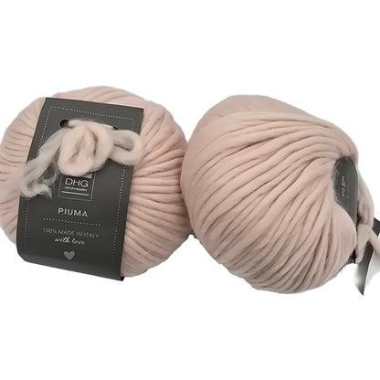 Image of two balls of Piuma by DHG Ultra Soft bulky Italian Merino Wool  yarn in the color Etoile which is a solid very pale pinky beige with labels on a white background