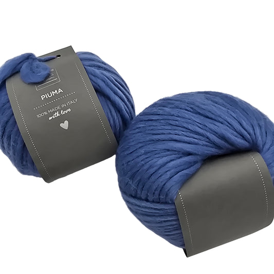 Image of two balls of Piuma by DHG Ultra Soft bulky Italian Merino Wool  yarn in the color Jeans which is a solid medium blue with labels on a white background