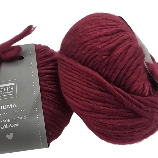 Image of two balls of Piuma by DHG Ultra Soft bulky Italian Merino Wool  yarn in the color Soft Fruit which is a solid burgundy with labels on a white background