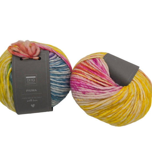 Image of two balls of Piuma by DHG Ultra Soft, bulky, Italian, Merino Wool  yarn in the color Unicorn which is a multicolor yarn with mixed yellows, pinks, and blues with labels on a white background.