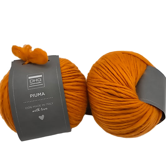 Image of two balls of Piuma by DHG Ultra Soft bulky Italian Merino Wool  yarn in the color pumpkin which is a solid orange with labels on a white background