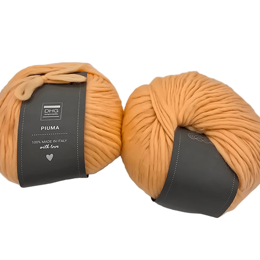 Image of two balls of Piuma by DHG Ultra Soft bulky Italian Merino Wool  yarn in the color Flamingo which is a solid light orange with labels on a white background