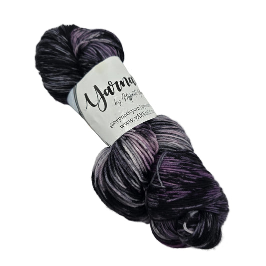 Image of a single hank of Plush Sock yarn by Hypnotic Yarn in the color Storm Watch with label on a white background.