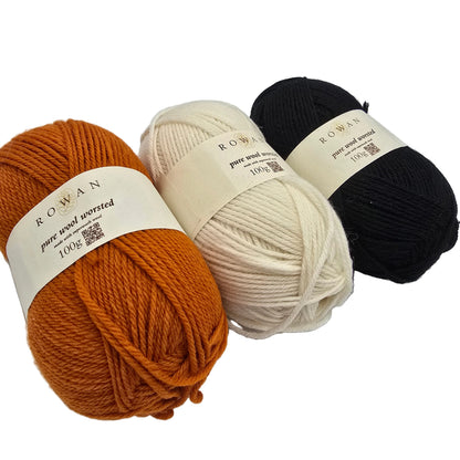 Three skeins of ROWAN Pure Wool Worsted yarn with labels in burnt orange, cream, and black, arranged diagonally on a white background.