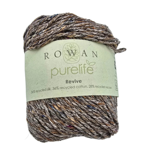 A skein of Rowan Purelife Revive yarn in color 462 Basalt with a light green paper label, showing a variegated blend of brown, beige, and muted blue fibers, on a plain white background.
