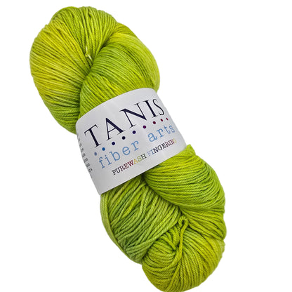 Image of a single skein of Purewash_Fingering_Yarn_by_Tanis_-in the color Lemongrass with label on a white background.