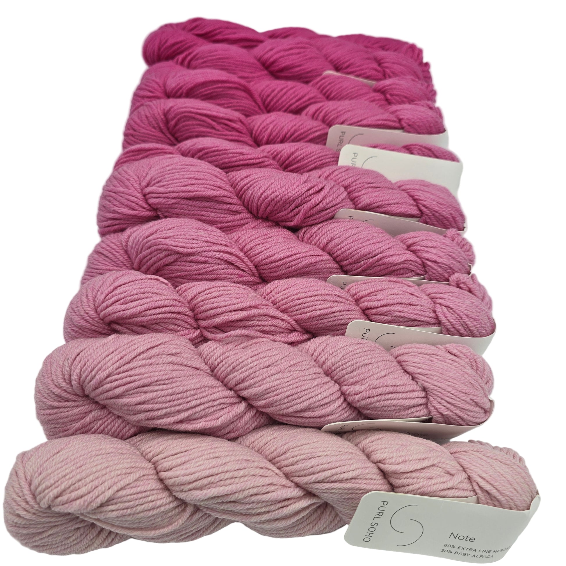 Image of a bundle of 10 skeins of yarn in a gradient from light to dark pink in a color called dragon fruit by the brand purl soho with labels on a white background.