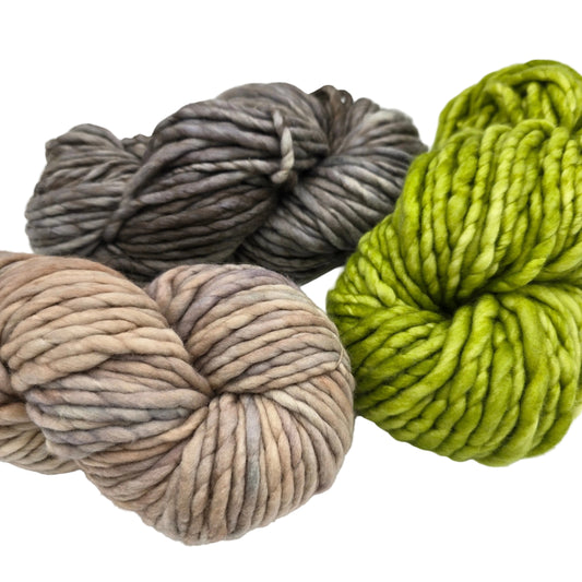 Three skeins of Rasta_By_Malabrigo chunky variegated yarn on a white background: one bright lime green, one taupe-beige with gray and mauve variegation, and one charcoal gray with taupe variegation. 