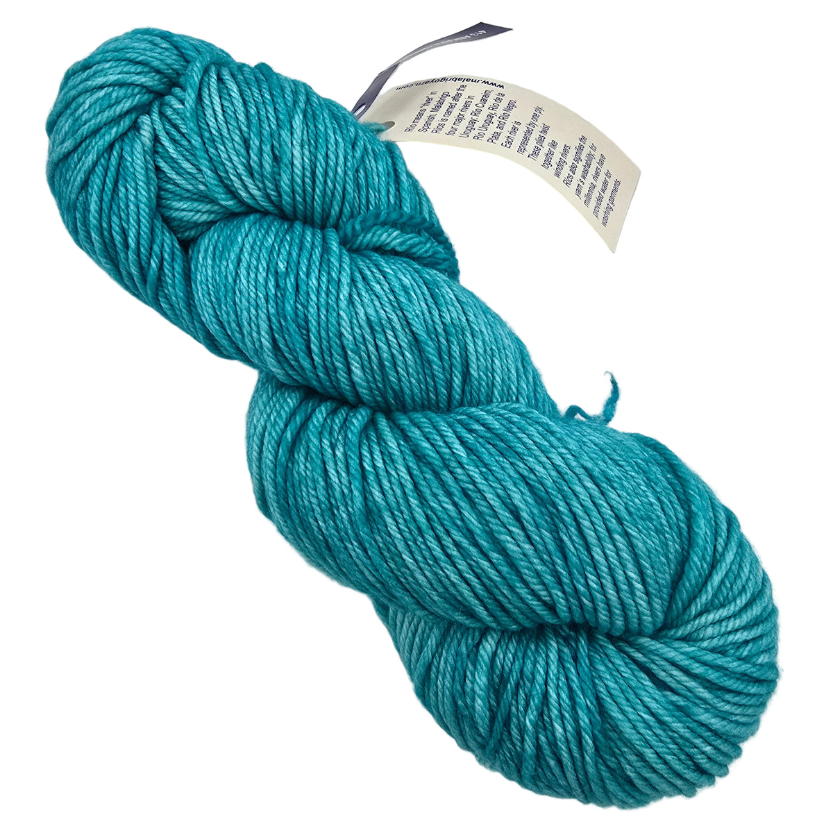 A skein of Rios_Yarn_by_Malabrigo_in color_413_Ankara_Green ateal blue yarn with a paper product tag attached, photographed on a plain light background.