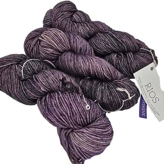 Image of three skeins of Dark Purple worsted Merino Wool Rio by Malabrigos  Yarn with label on a white background.
