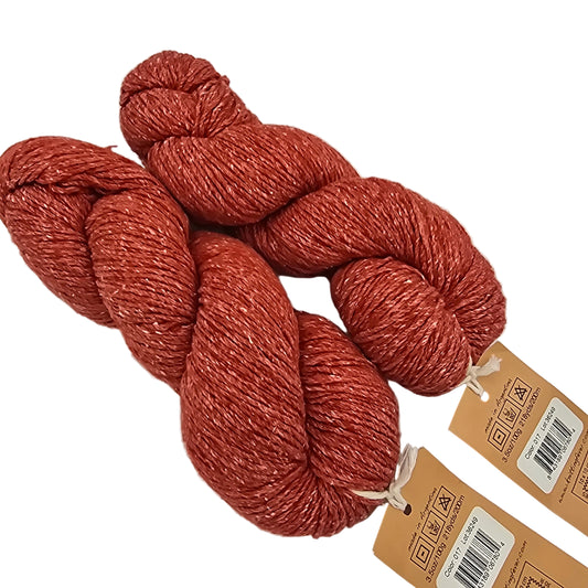 Three skeins of rust-colored yarn with tags on a light gray background