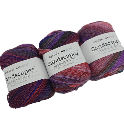 Image of three cakes of Sandscapes by Knit Picks  yarn in the color Betta with labels on a white background.