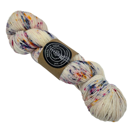 Image of a single skein of Seed Fingering by Heidi & Lana  in the color Sunkissed with label on a white background.