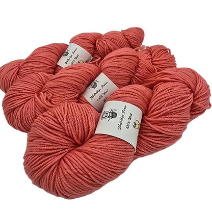 Image of 3 skeins of Shelrudge farm yarn in the color passion which is a coral pink with labels on a white background.