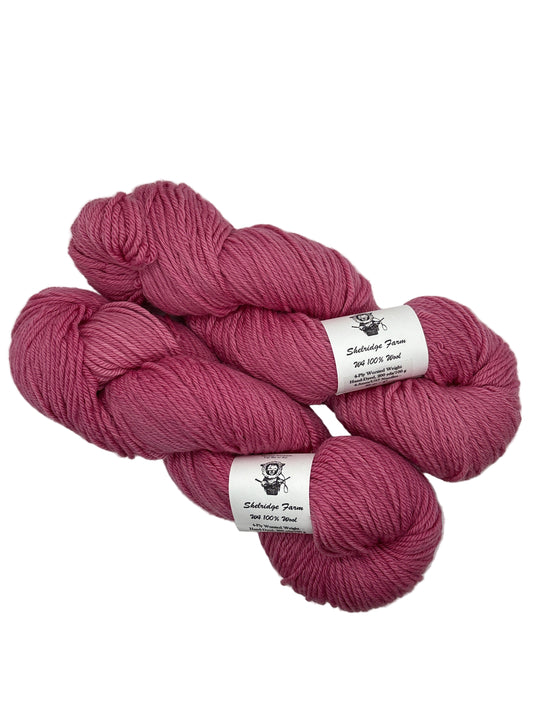 Three skeins of pink yarn with labels on a white background