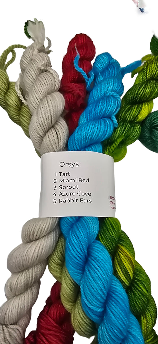 Image of multiple different colored mini skeins of Smooshy Cashmere by Dream yarn in color package named Orsys with label on white background.