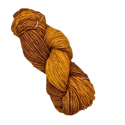 Image of a Studio Worsted Double Skein of yarn by Neighborhood Fiber Co. in the color Del Rey  a warm gradient from deep rust brown to golden ochre on a white background.