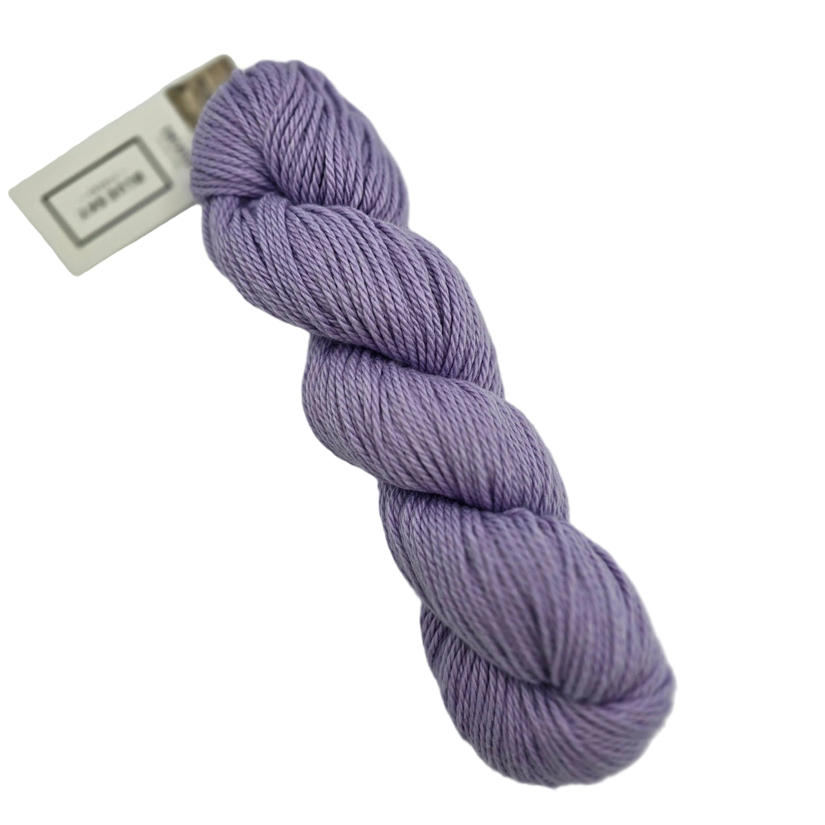 A skein of Sweater Worsted Yarn by Blue Sky Fibers in the color Lilac a light purple yarn with a paper label attached, photographed on a clean white background.