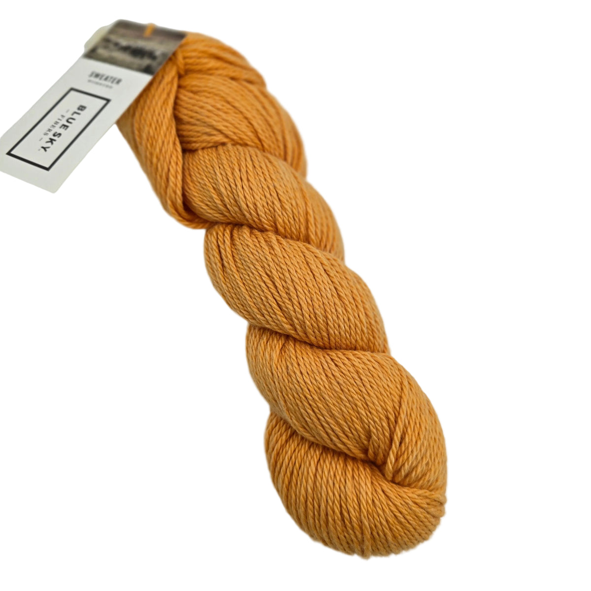 A skein of Sweater Worsted Yarn by Blue Sky Fibers in the color Pollen an orange yarn with a paper label attached, photographed on a clean white background.
